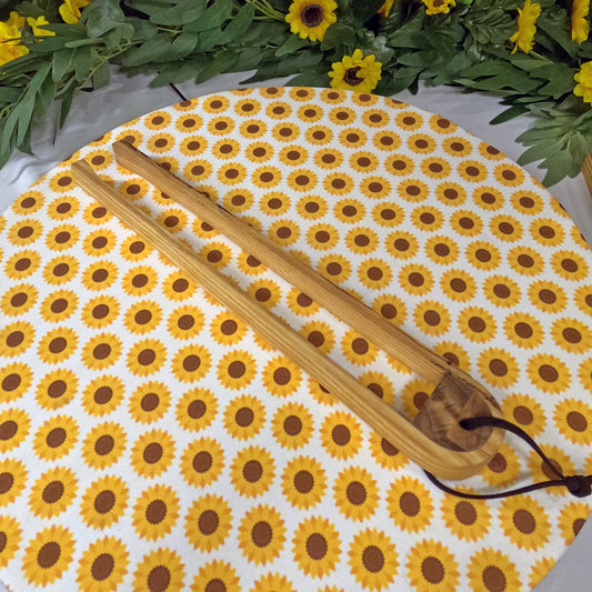 Round sunflower-patterned placemat with Wooden tongs on a white background