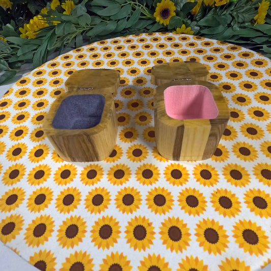 Two wooden jewelry boxes with colorful cushions on a sunflower-patterned tablecloth.