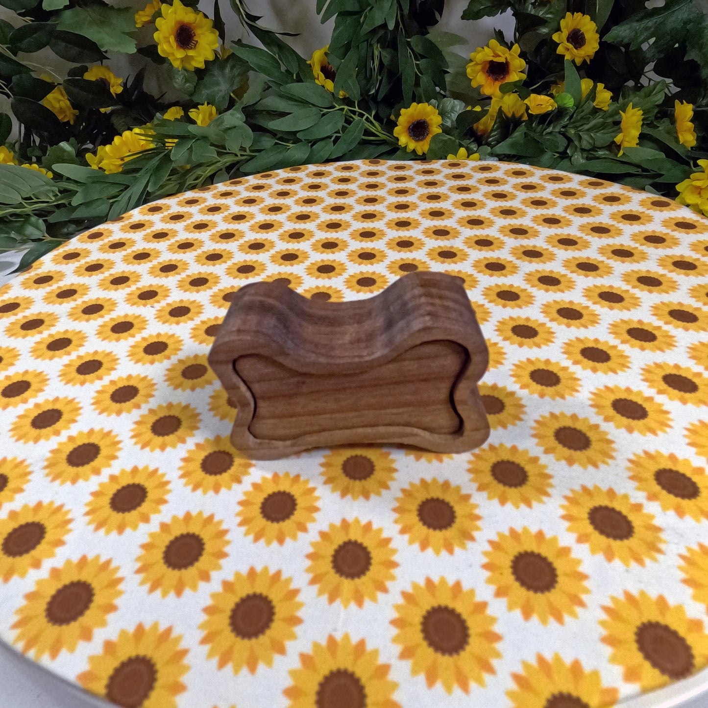 Wooden dog bone-shaped box on a tablecloth with sunflower pattern