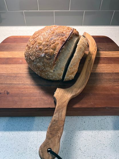 Loaf of bread on a wooden board with a bread knife