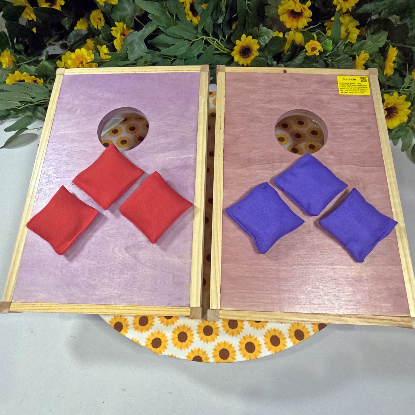 Two wooden cornhole boards with red and blue bean bags on a floral background