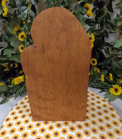 Wooden mitten-shaped object on a table with a floral background