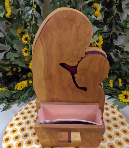 Wooden box with a silhouette of a person on top, set against a floral background.