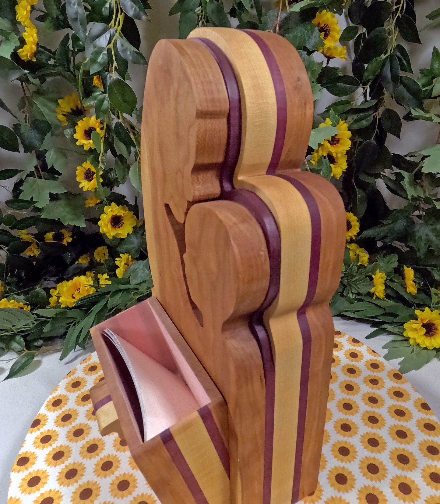 Wooden sculpture with purple and yellow stripes on a floral tablecloth