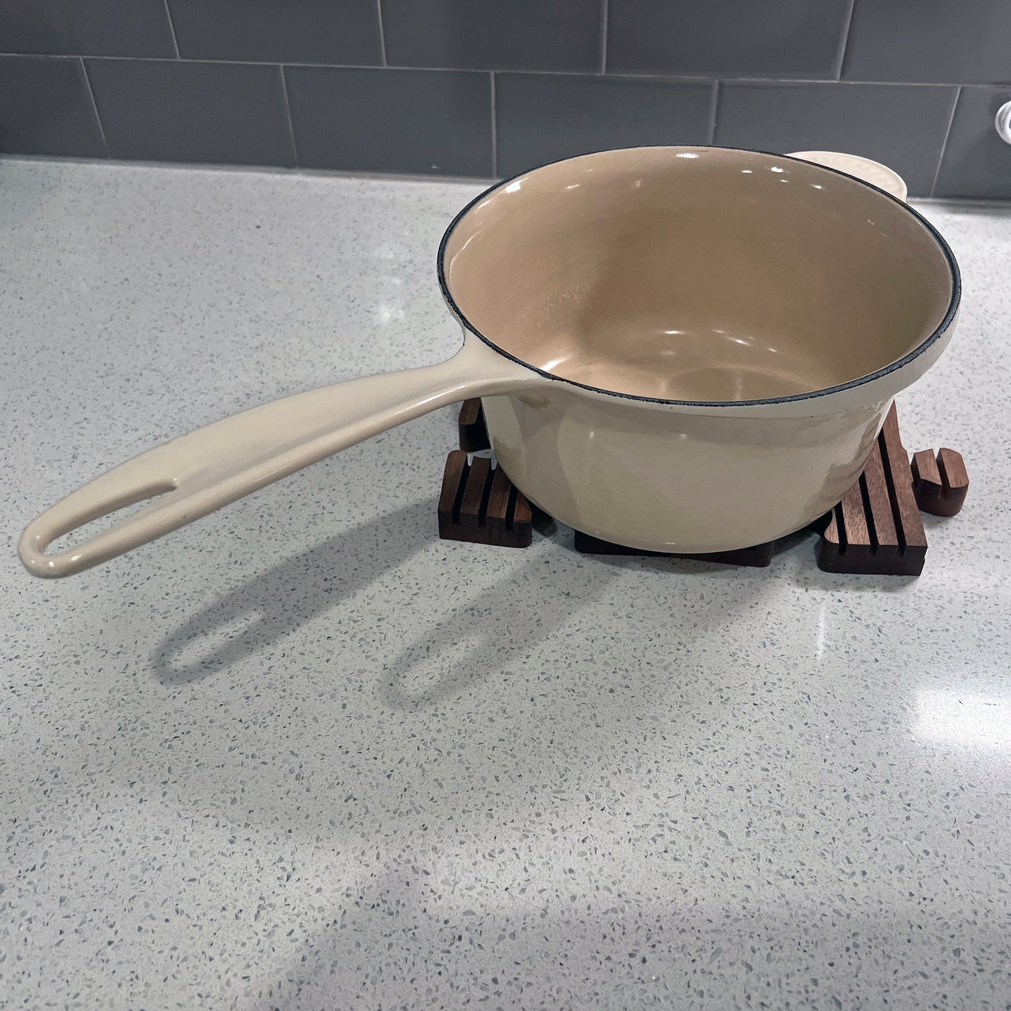 Beige pot on a gray countertop with a tiled wall background