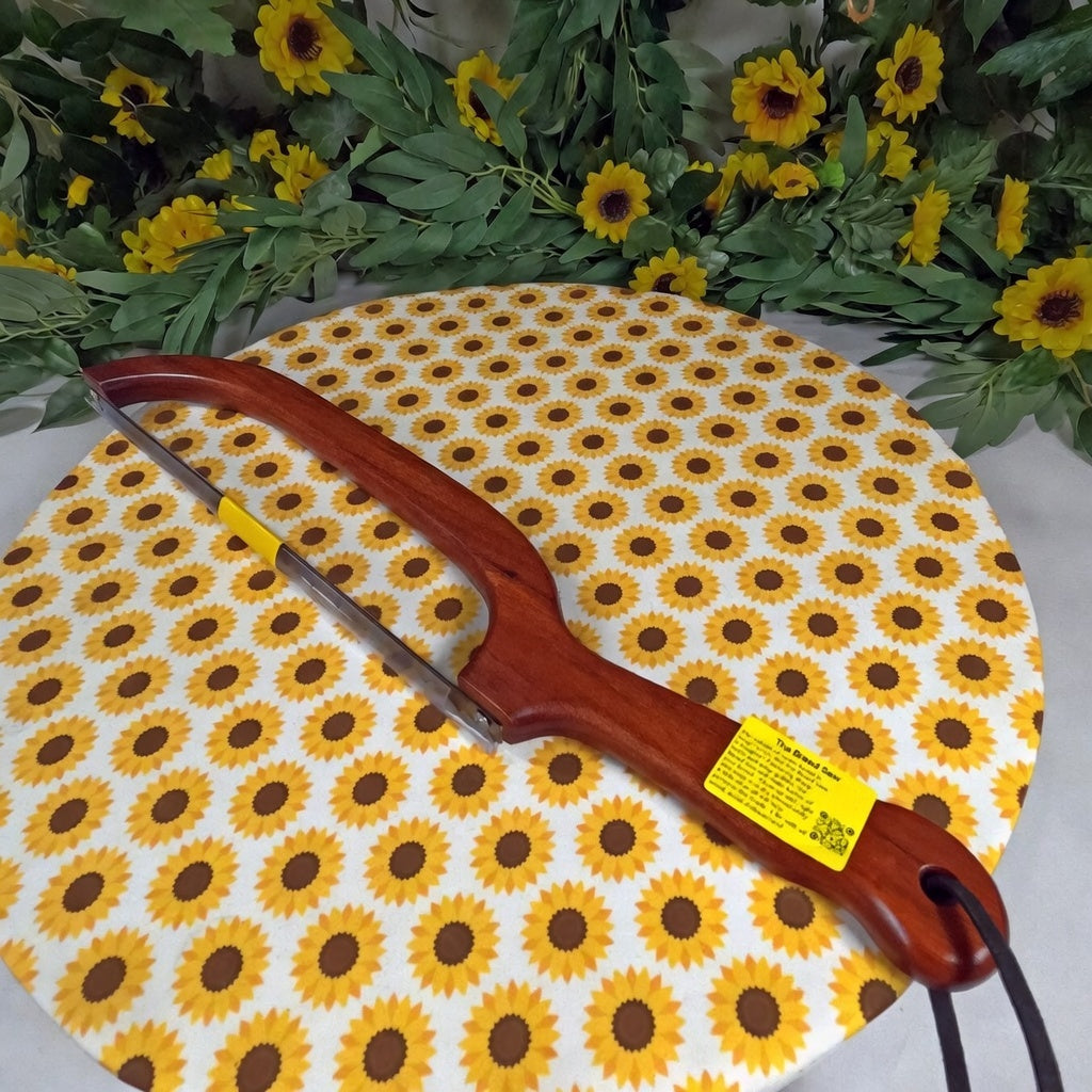Wooden bread saw and arrow on a sunflower-patterned mat with flowers and leaves in the background