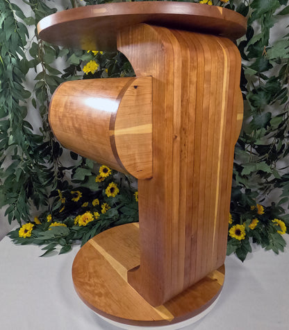 Wooden pedestal side table with a unique design against a floral background
