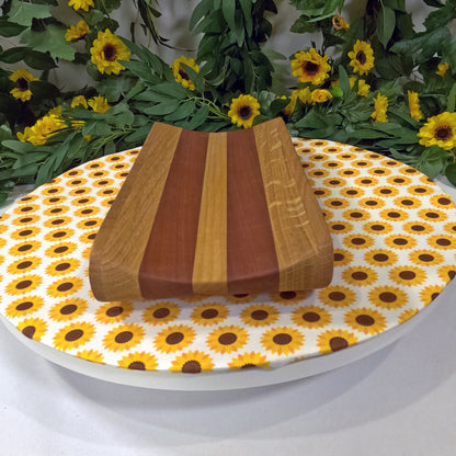 Wooden tray on a plate with sunflower pattern, surrounded by greenery and flowers.