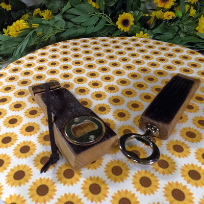 Two wooden bottle openers on a tablecloth with sunflower pattern