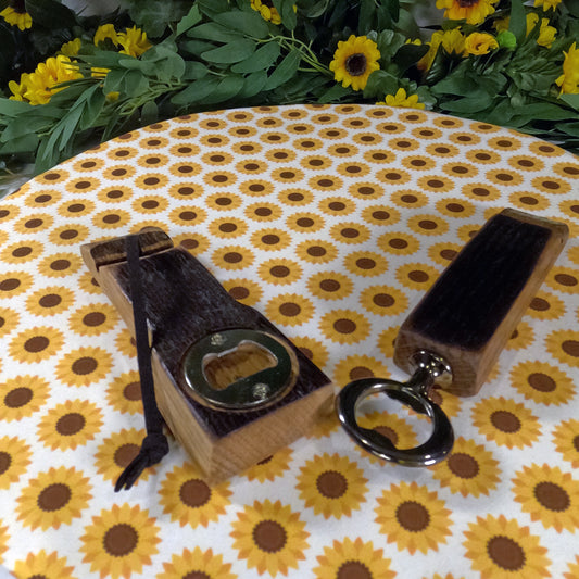 Two wooden bottle openers on a tablecloth with sunflower pattern