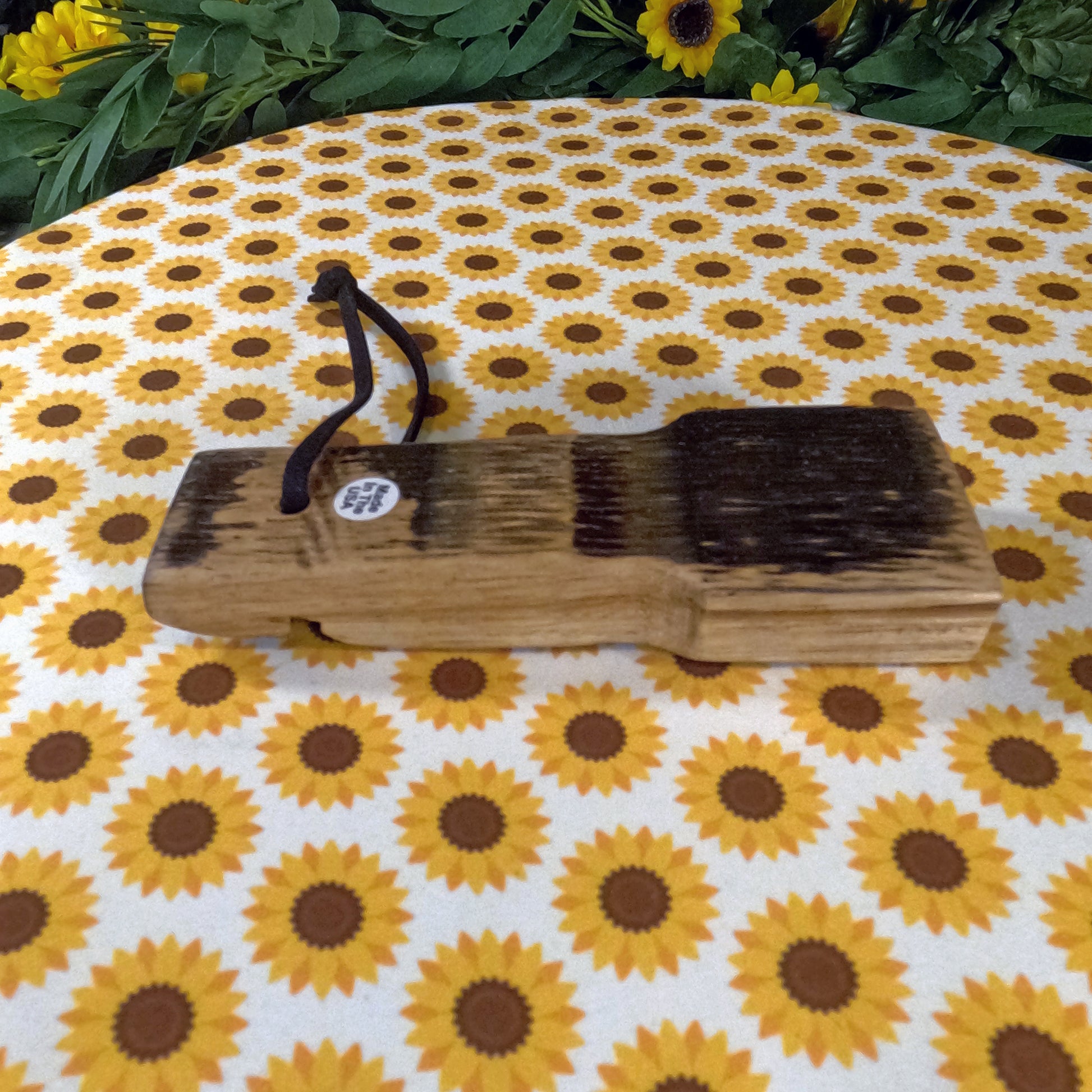 Wooden bottle opener on a sunflower-patterned fabric background