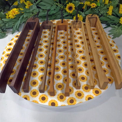 Set of Wooden tongs on a sunflower-patterned mat with greenery in the background