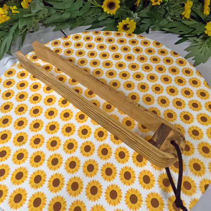 Wooden tongs on a sunflower-patterned mat with greenery around