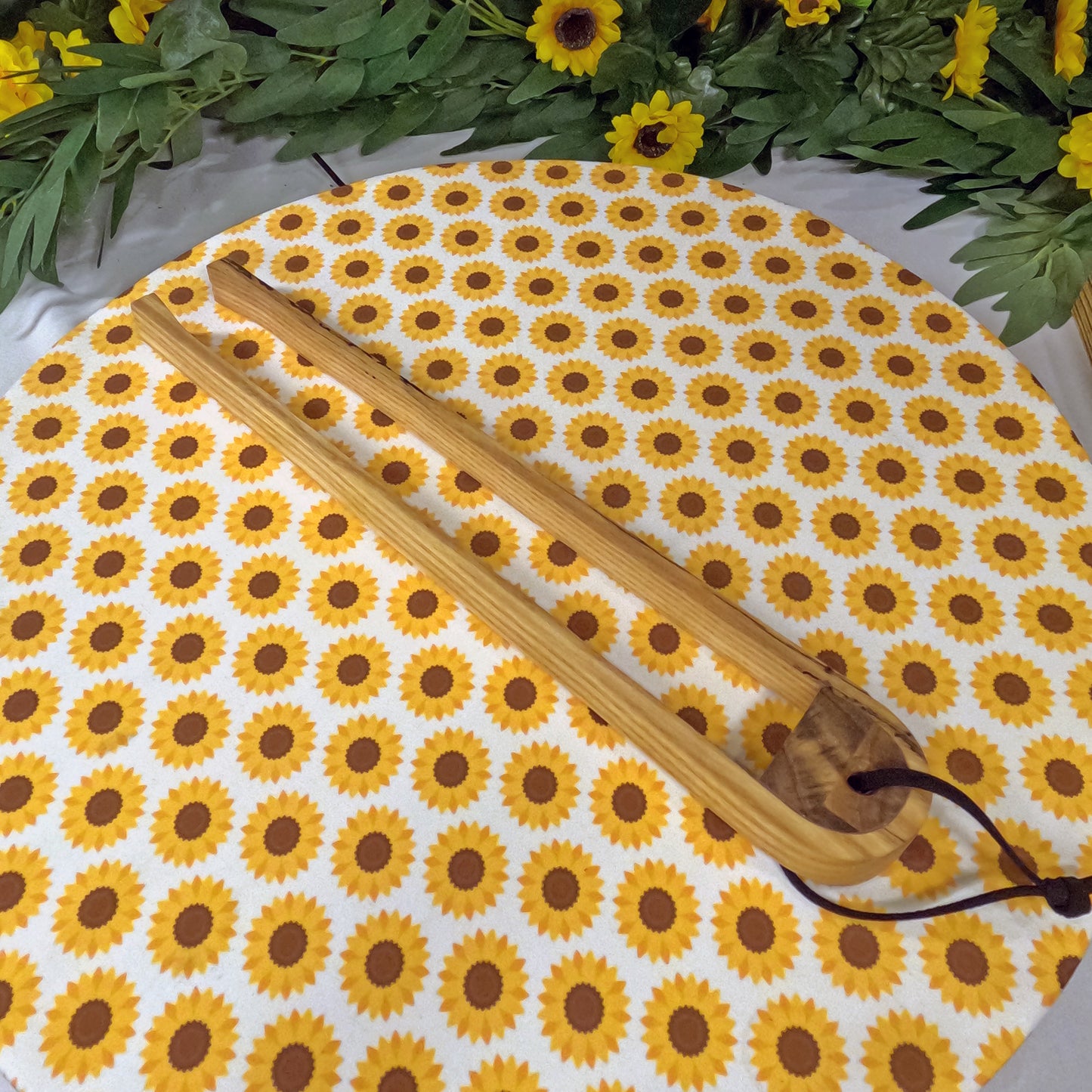 Round sunflower-patterned placemat with Wooden tongs on a white background