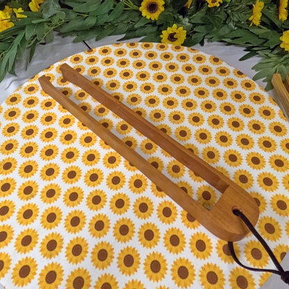 Wooden tongs with sunflower pattern on a white background