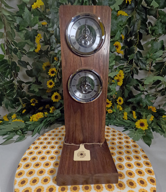 Wooden clock with two faces on a floral-patterned surface with greenery in the background