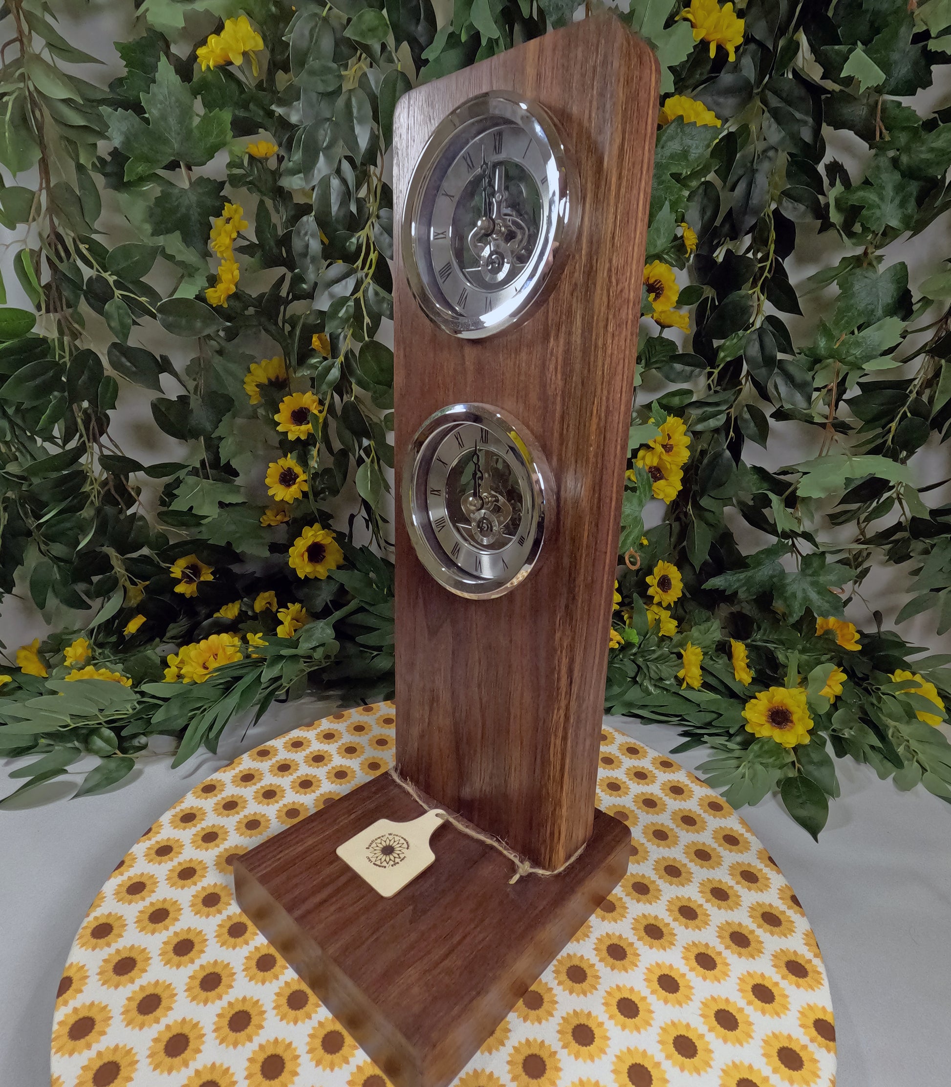 Wooden clock with silver circular faces on a floral-patterned tablecloth