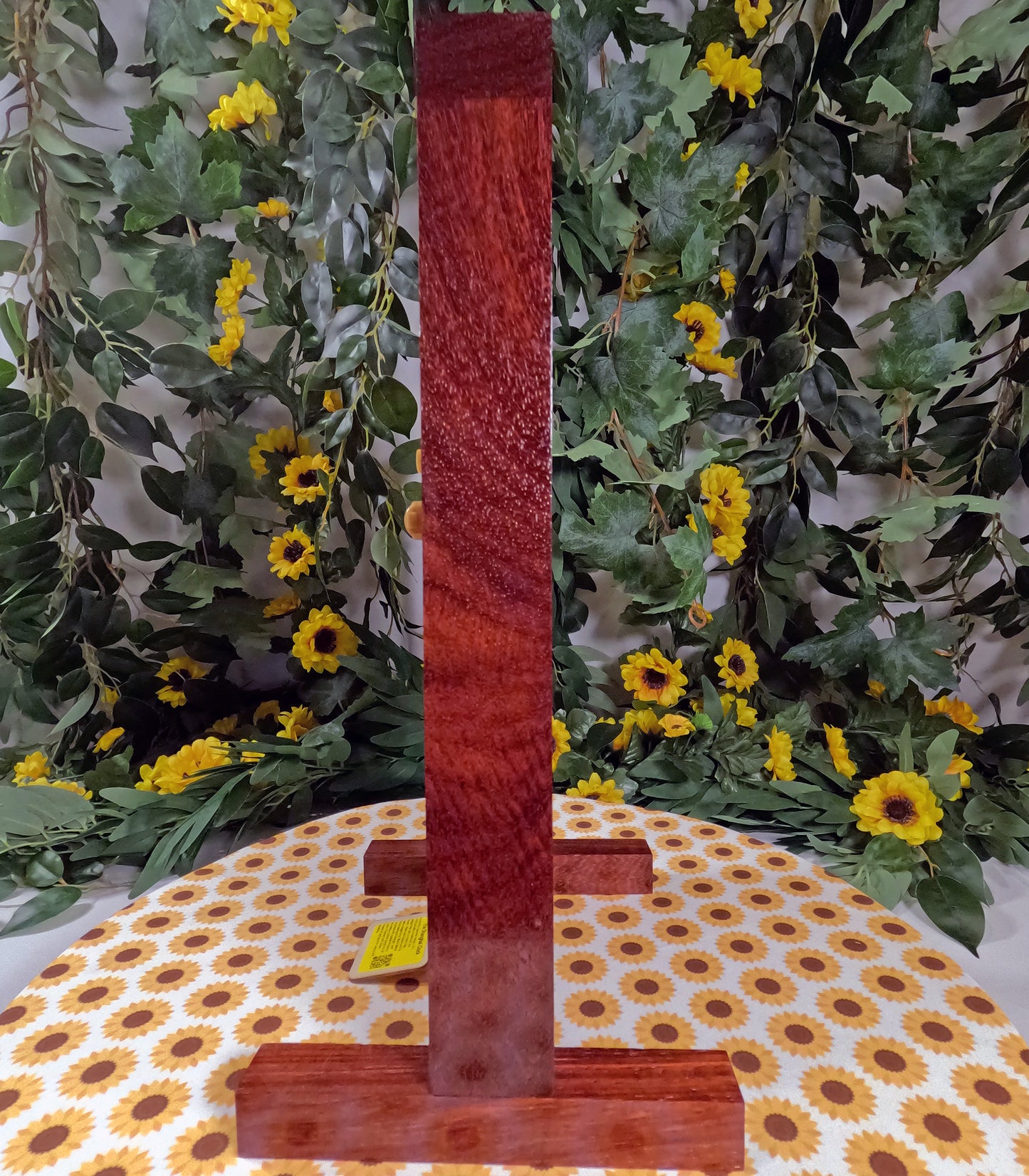 Red textured object on a stand with a floral and polka dot tablecloth background