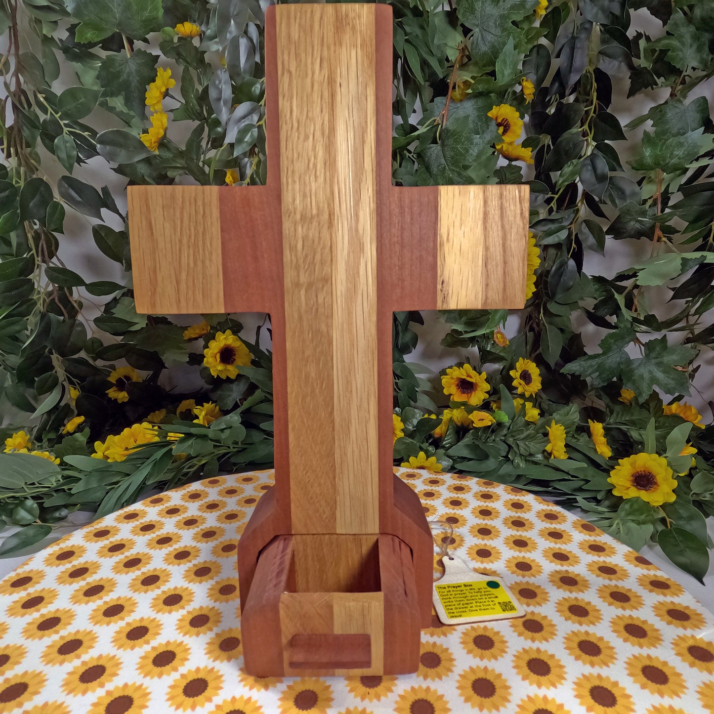 Wooden cross on a table with floral and greenery background