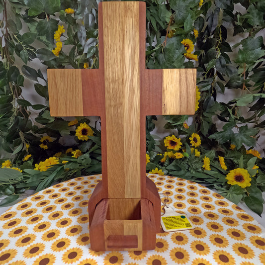 Wooden cross on a table with floral and greenery background