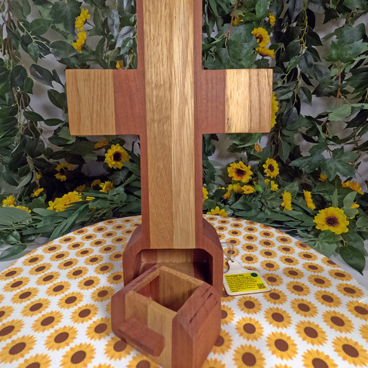 Wooden cross with a decorative background of greenery and sunflowers
