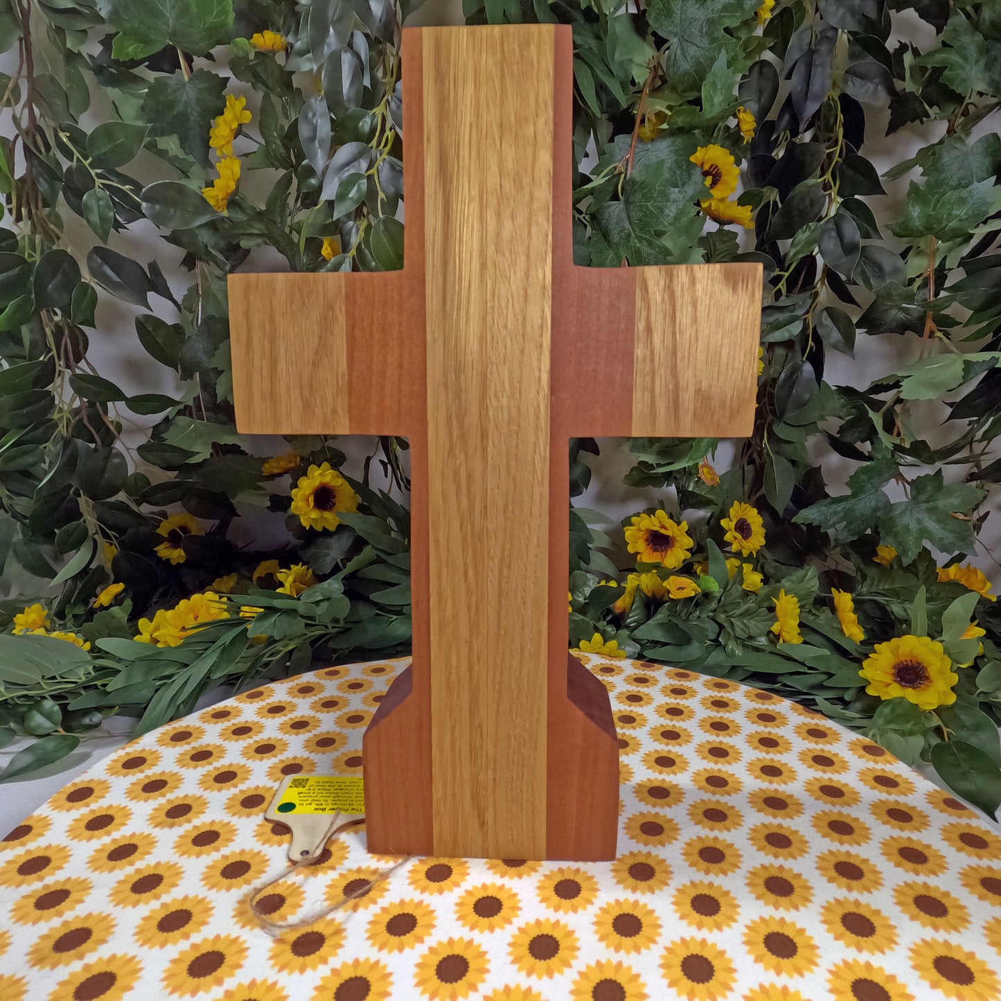 Wooden cross on a tablecloth with floral and greenery background