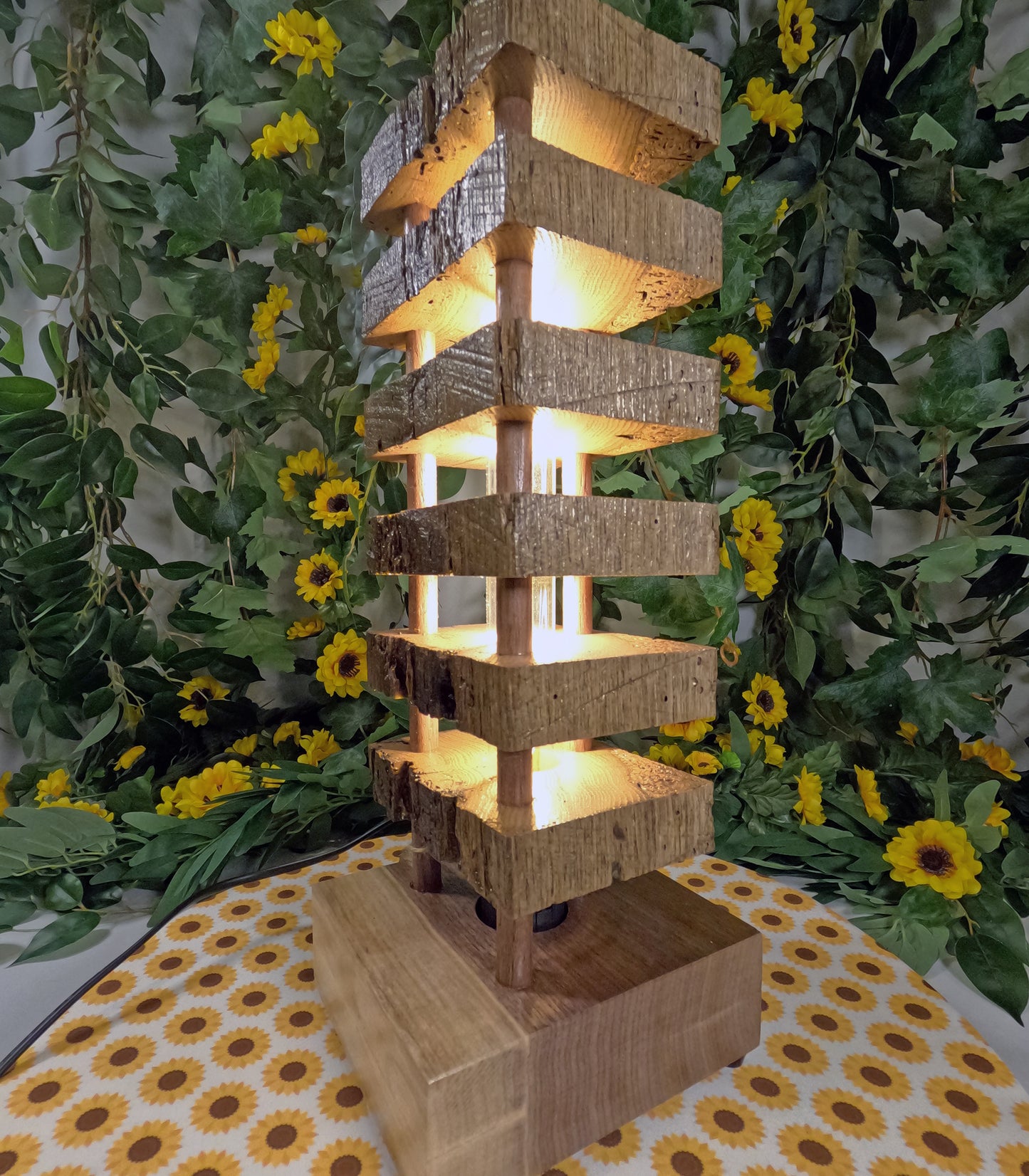 Wooden lantern with a warm glow surrounded by greenery and yellow flowers