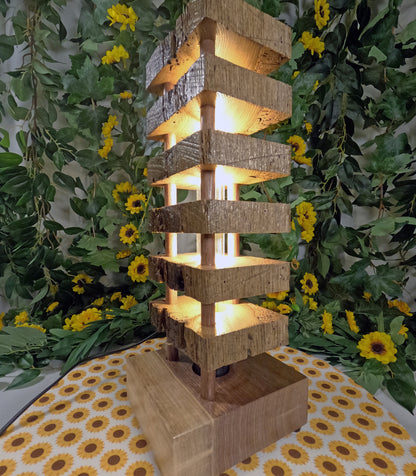 Wooden lantern with a warm glow surrounded by greenery and yellow flowers