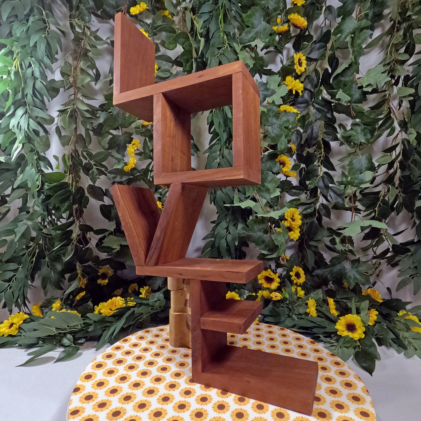 Wooden geometric shelf against a green leafy and floral background