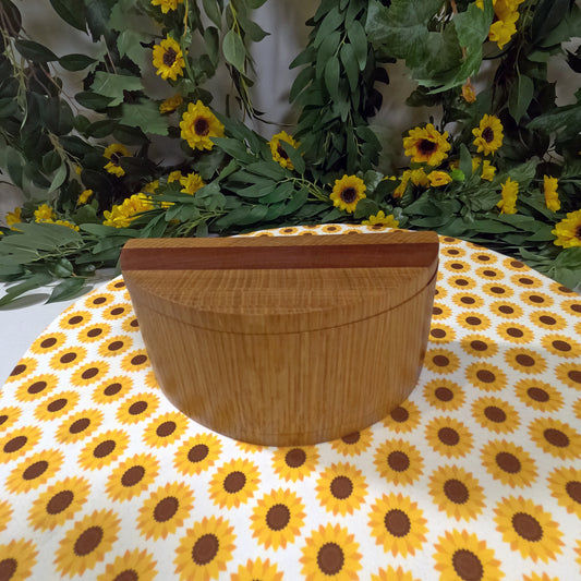 Wooden box on a tablecloth with sunflower pattern, surrounded by greenery and flowers.