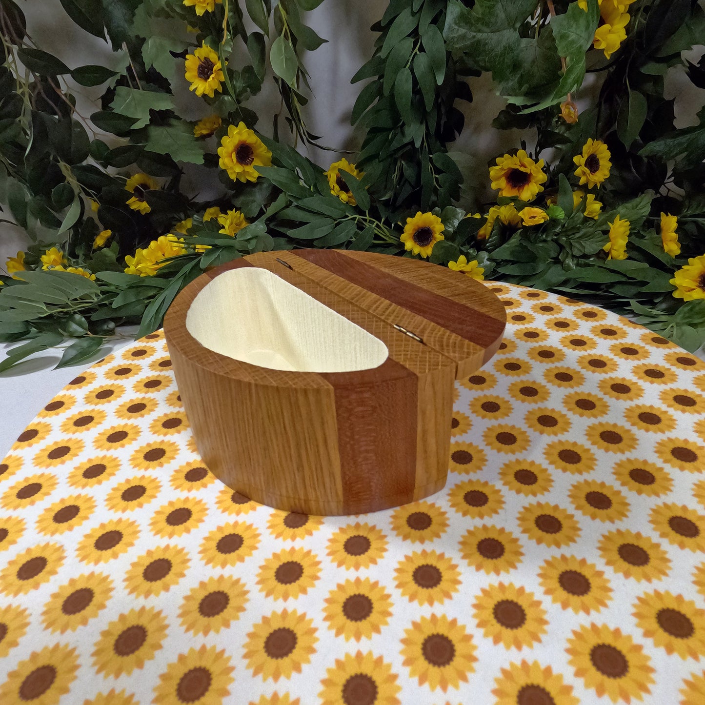 Wooden box on a sunflower-patterned tablecloth with floral decorations in the background.