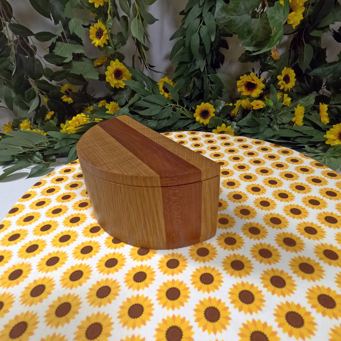 Wooden box on a sunflower-patterned tablecloth with greenery in the background