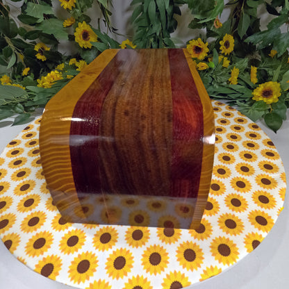 Wooden vase on a sunflower-patterned tablecloth with greenery and flowers in the background