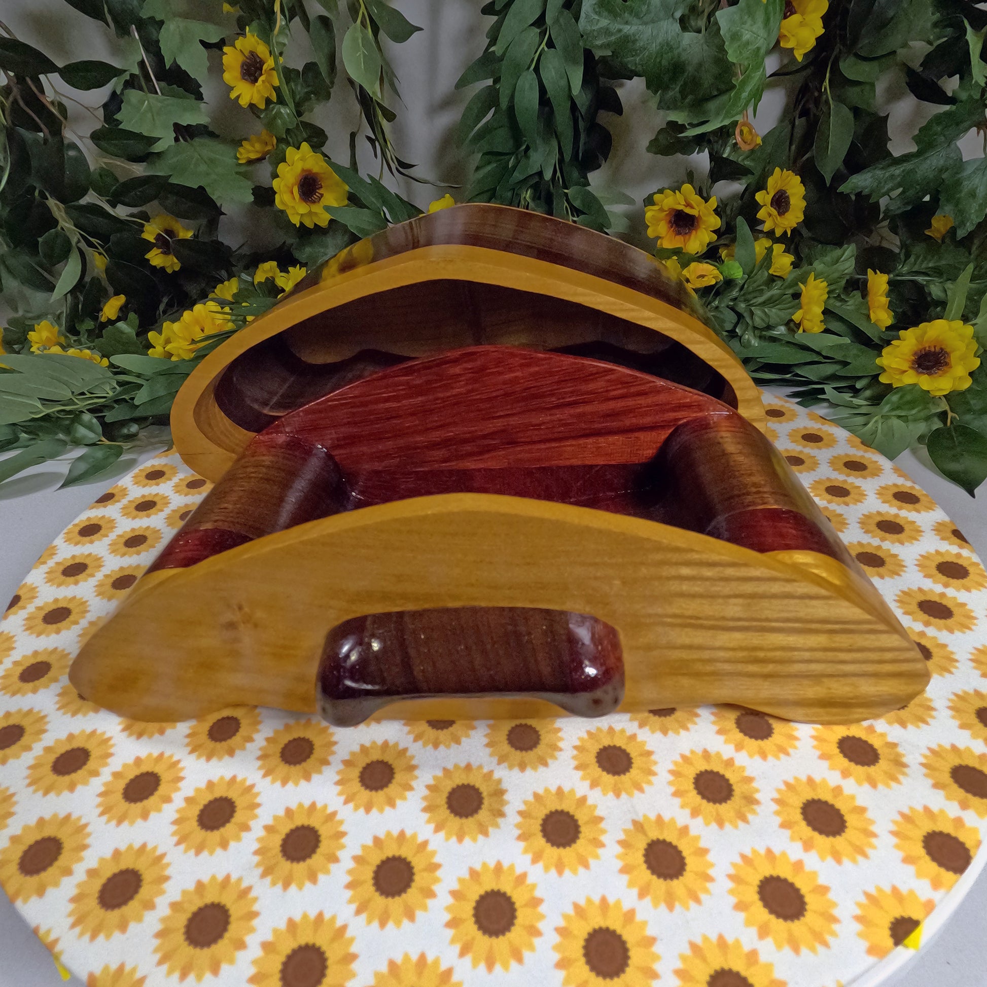 Wooden box with red interior on a sunflower-patterned surface with greenery