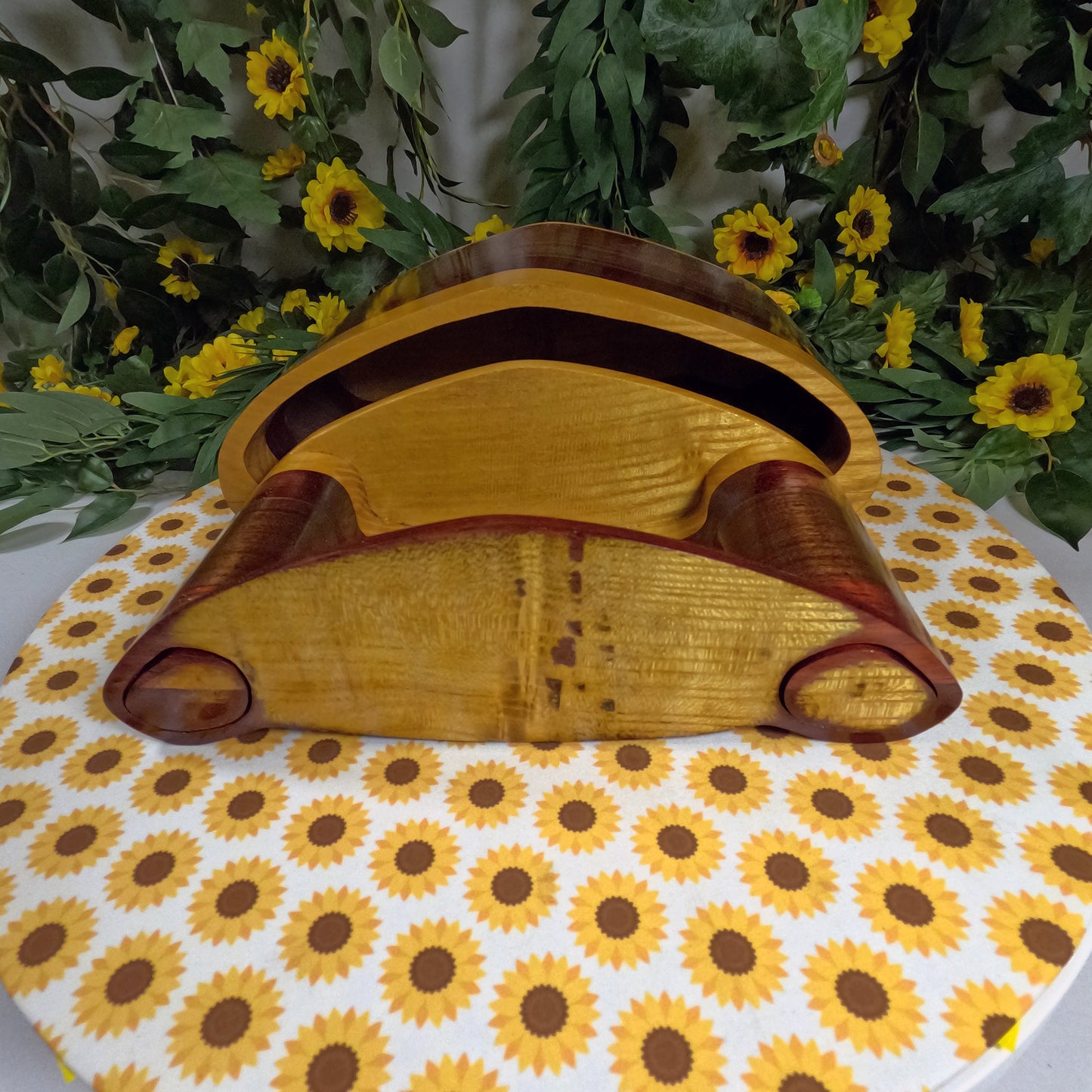 Wooden box with a unique design on a sunflower-patterned tablecloth.