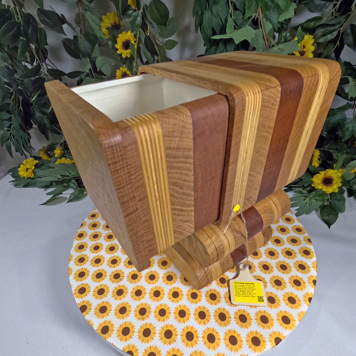 Wooden jewelry box with striped pattern on a floral-patterned tablecloth