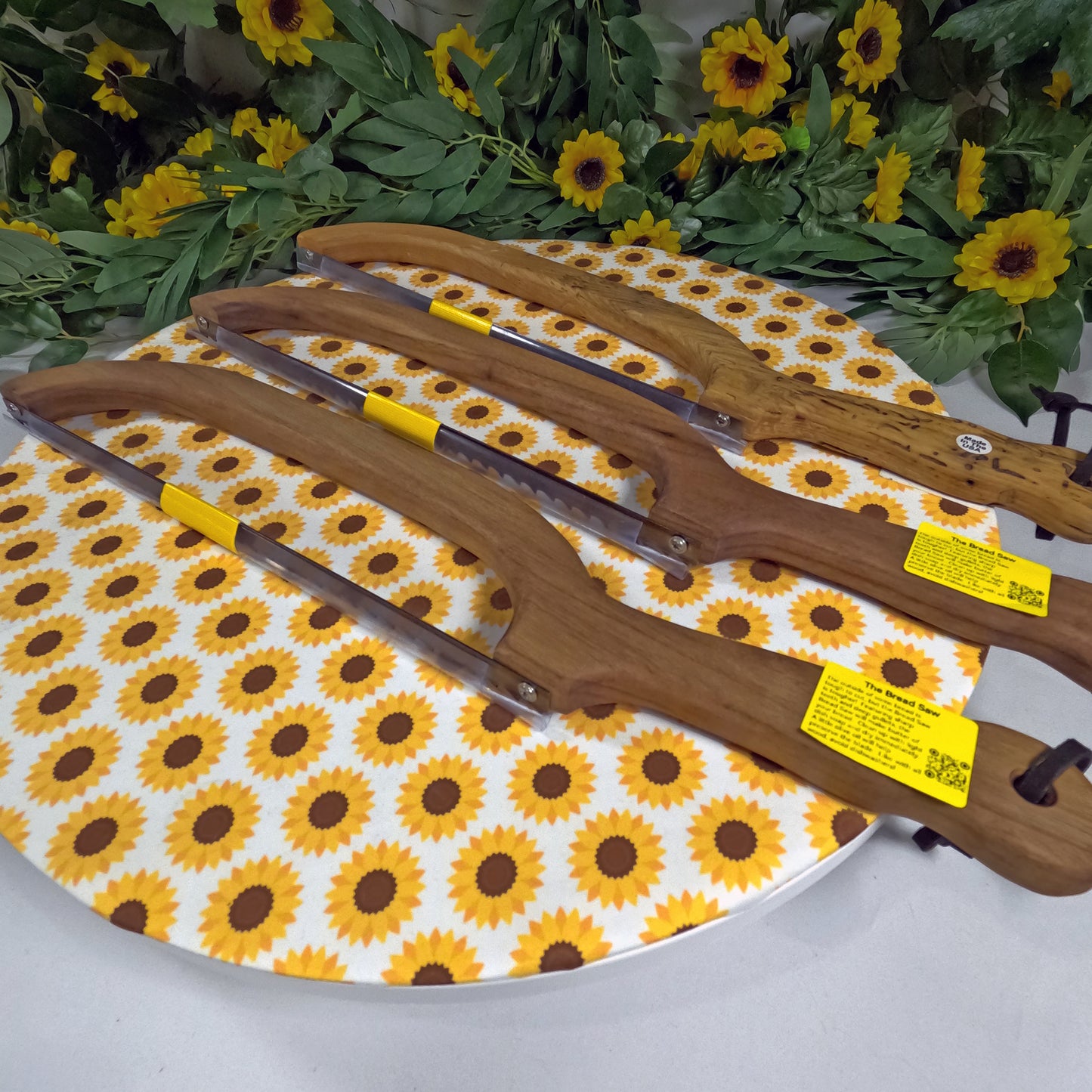 Wooden saws on a sunflower-patterned ironing board with greenery in the background