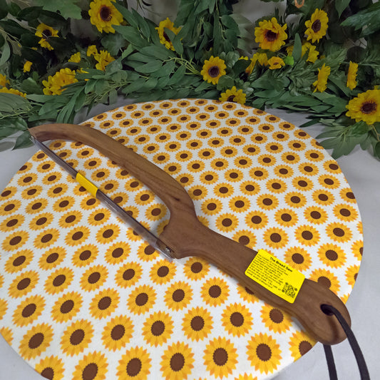 Wooden saw with a yellow label on a sunflower-patterned mat, surrounded by sunflowers and greenery.