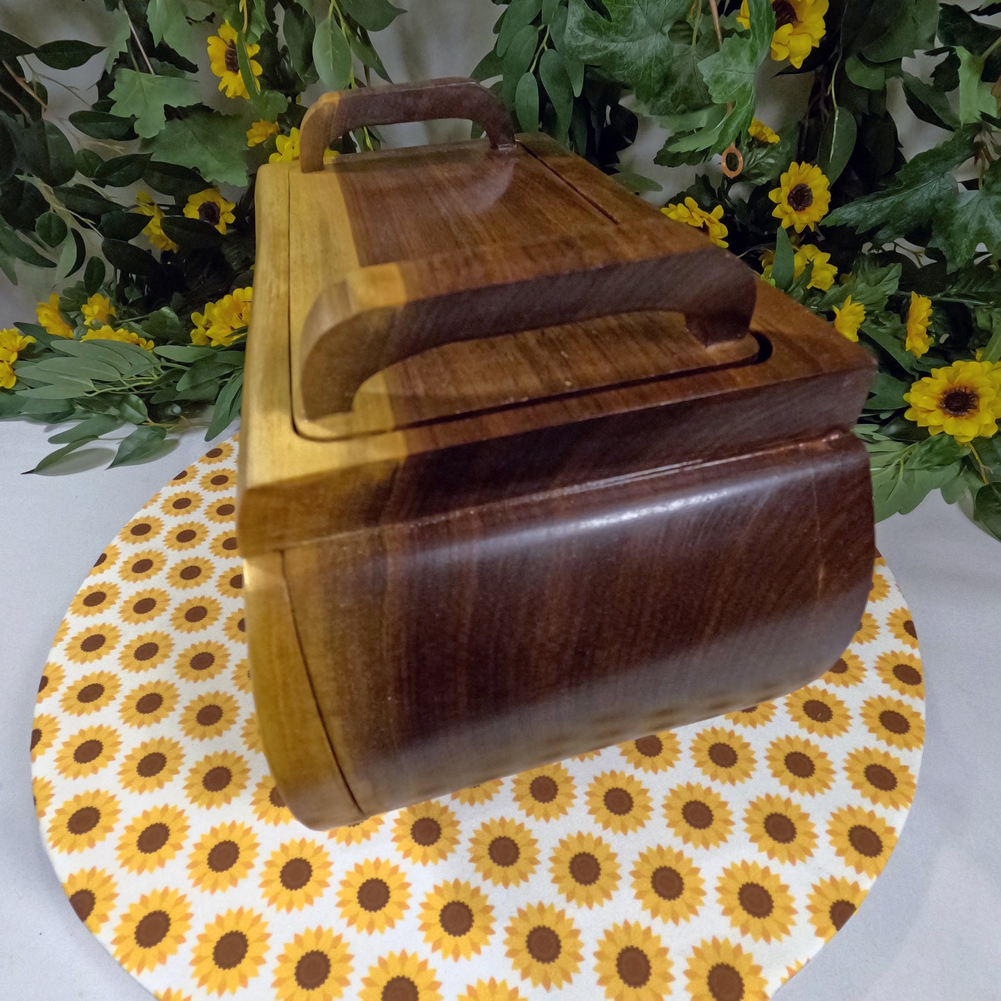 Wooden box with a lid on a sunflower-patterned tablecloth with flowers in the background