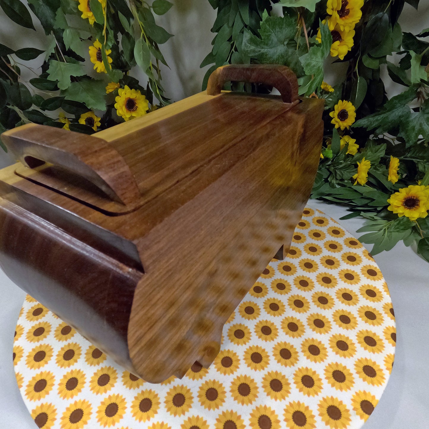 Wooden jewelry box on a table with sunflower-patterned tablecloth and floral background