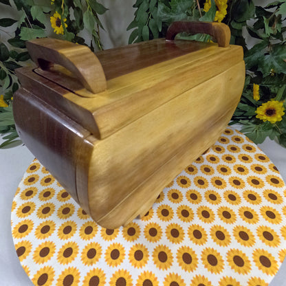 Wooden jewelry box on a sunflower-patterned mat with greenery in the background