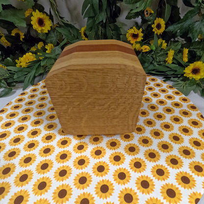Wooden box on a tablecloth with sunflower pattern, surrounded by greenery and yellow flowers.
