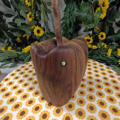 Wooden apple-shaped object with a green eye on a tablecloth with sunflower pattern