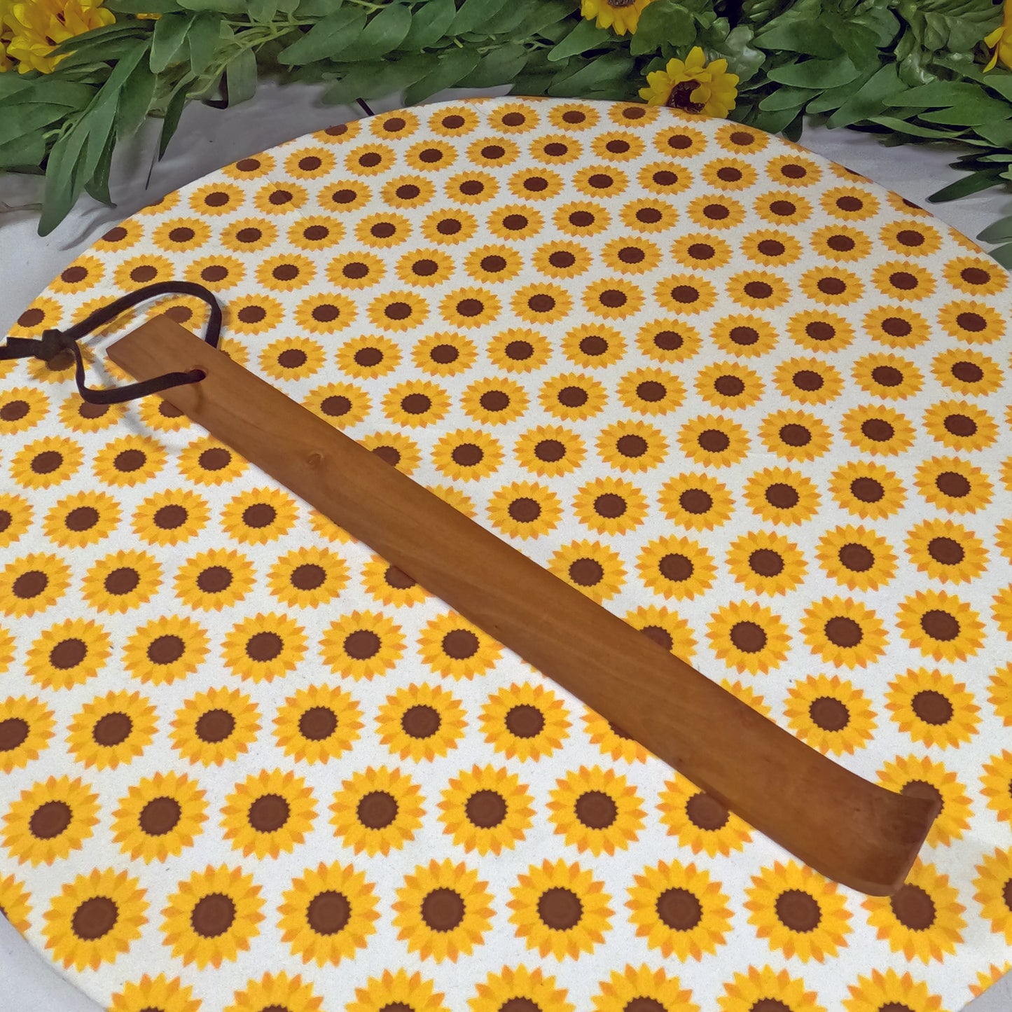 Wooden back scratcher with sunflower pattern and  on a white background