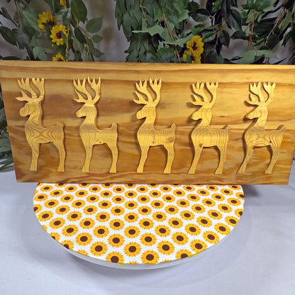 Wooden wall art with deer carvings and a sunflower-patterned plate below.