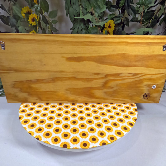 Wooden placque with a sunflower patterned base on a white surface.