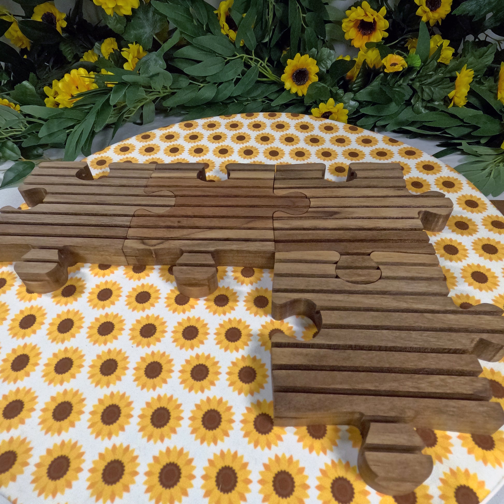 Wooden puzzle trivets shaped like an L on a sunflower-patterned tablecloth.