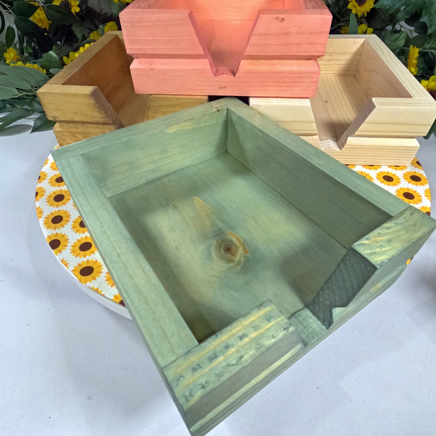 Green wooden box on a white surface with sunflower-patterned paper underneath