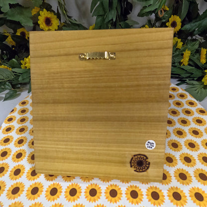 Wooden block with a decorative emblem on a sunflower-patterned tablecloth