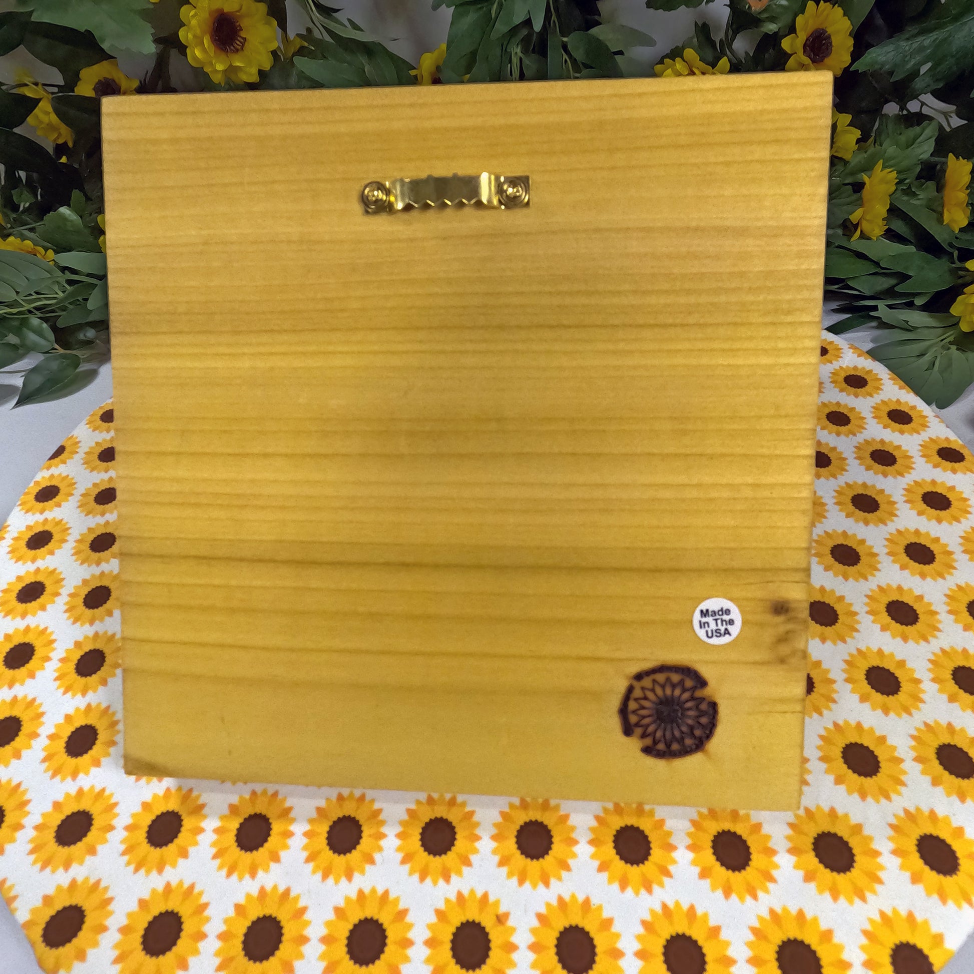 Wooden block with a gold handle on a sunflower-patterned surface